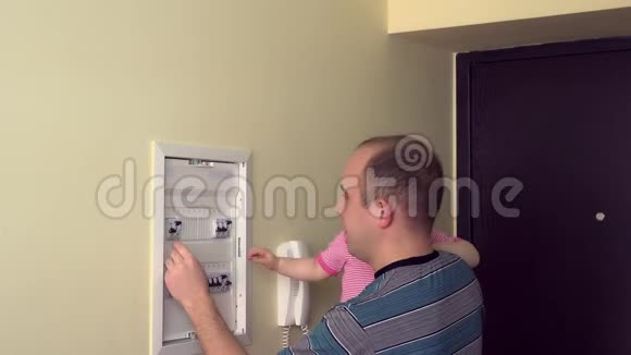男人带着女婴检查房间里的电器断路器4K视频的预览图