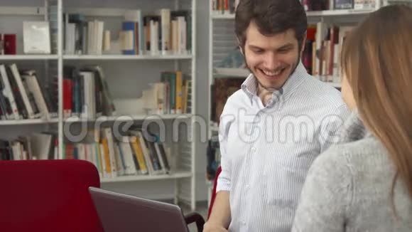 男同学在图书馆给女同学看笔记本电脑上的东西视频的预览图