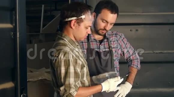 两个木匠在车间里讨论一些事情在平板上看一些东西视频的预览图
