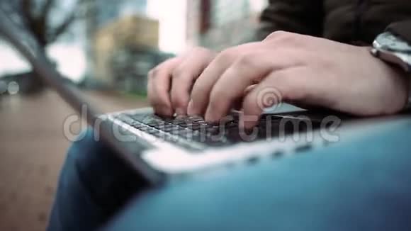 年轻人用他的笔记本电脑在街头长凳上打字从上面看4k手的细节视频的预览图
