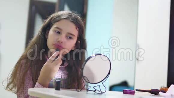 小女孩用室内口红涂嘴唇女学生在镜子前涂红唇膏视频的预览图