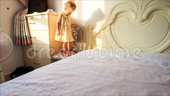 小女孩在地板上爬上爬下的白色床视频的预览图