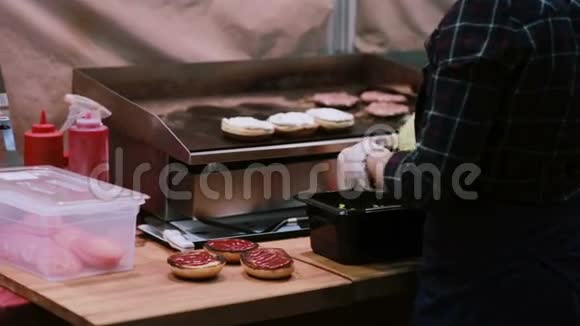 一位白手套的厨师用新鲜沙拉做汉堡在烤架上烤生肉做汉堡背面视频的预览图