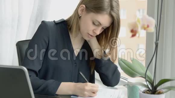 年轻的女商人在办公室工作写下笔记微笑着视频的预览图