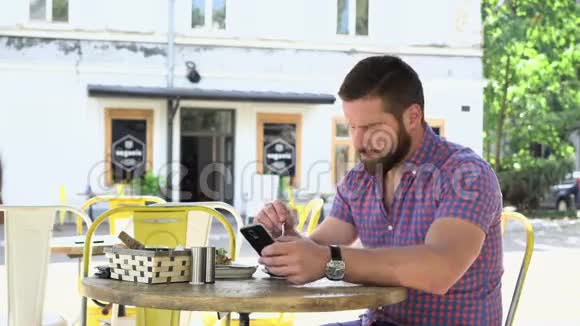 男人喝咖啡浏览智能手机视频的预览图