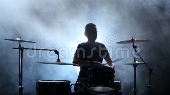 职业音乐家用棍子在鼓上演奏音乐烟熏背景剪影视频的预览图