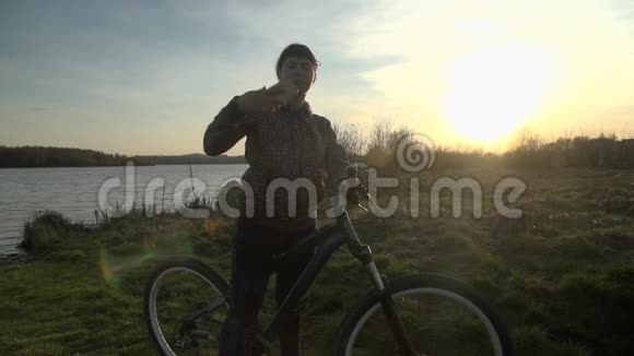 年轻女子骑自行车在日落时使用电话视频的预览图
