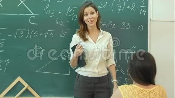 微笑老师在课堂上谈论绿色黑板上的数学任务视频的预览图