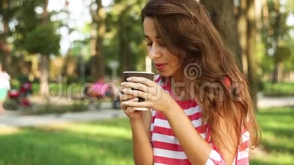 漂亮的女人坐在长凳上吃着松饼和拿铁视频的预览图