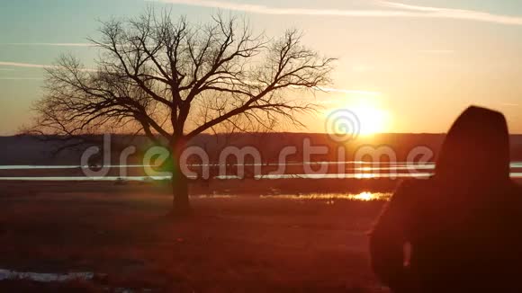 剪影两人在夕阳下的路上独自站在树上剪影运动的年轻人在大自然中奔跑视频的预览图