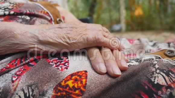 老年妇女的双手起皱坐在户外的老奶奶的手臂关闭侧视视频的预览图