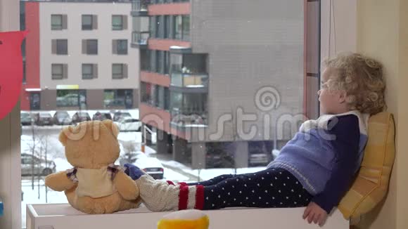 幼儿女孩和泰迪熊说话兴奋地看到外面的雪视频的预览图