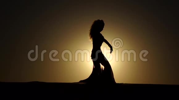 女孩在日落背景下表演美丽的肚皮舞剪影慢动作视频的预览图