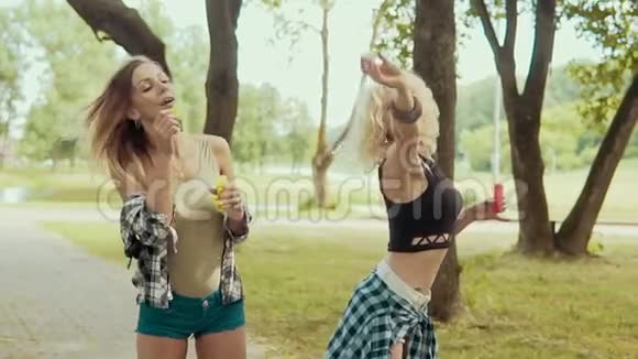 带着太阳镜的快乐时髦女孩在公园玩泡泡视频的预览图