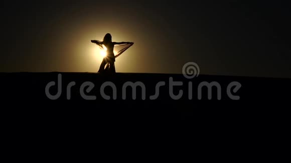 女孩在日落背景下表演美丽的肚皮舞剪影慢动作视频的预览图