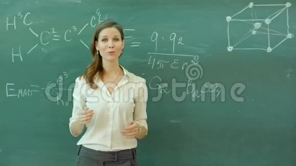 年轻快乐的女教师双臂交叉站在绿色的木板上视频的预览图