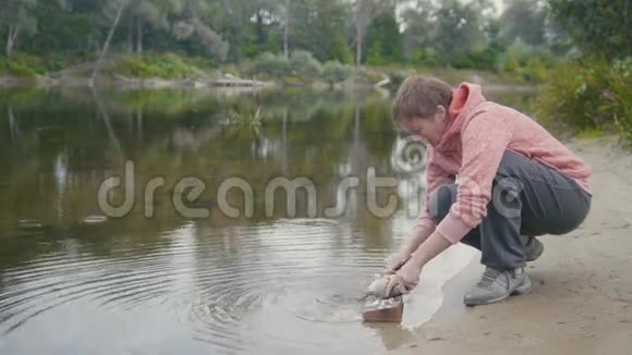 靠近森林河的女人用刀清洗鱼户外视频的预览图