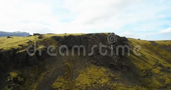 鸟瞰绿色熔岩田与凸起覆盖苔藓无人机飞过冰岛的山脉和悬崖视频的预览图