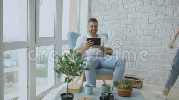 年轻有魅力的情侣们坐在现代阁楼公寓的阳台上用平板电脑在线视频聊天视频的预览图