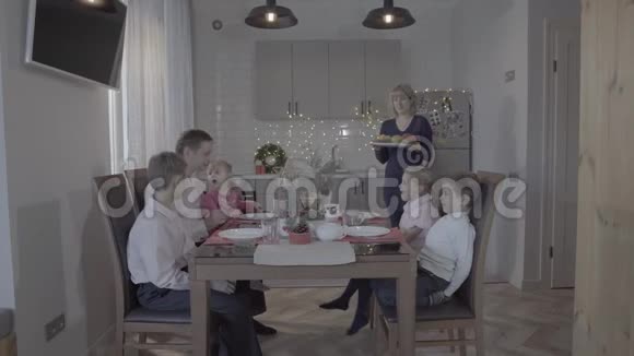 快乐可爱的四个孩子一家人庆祝新年厨房餐桌父亲儿子女儿笑妈妈端饭视频的预览图