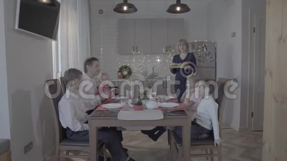 可爱快乐的四个孩子一家人庆祝新年厨房餐桌爸爸儿子女儿笑妈妈正在供应晚餐视频的预览图