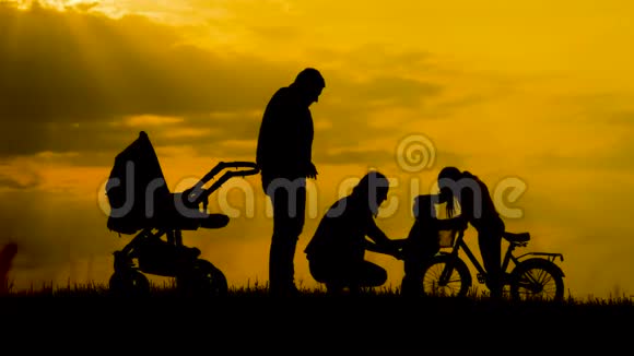 日落时分快乐的父母和他们的孩子在户外玩得很开心剪影视频的预览图
