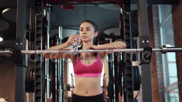 瘦女孩正在健身房里喝瓶子里的水运动服运动员在训练中休息视频的预览图