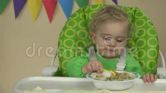 独立男婴用勺子坐在喂饭椅上吃粥视频的预览图