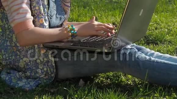 一个带着笔记本电脑的十几岁女孩公园里的女孩在用笔记本电脑工作手拿手镯视频的预览图