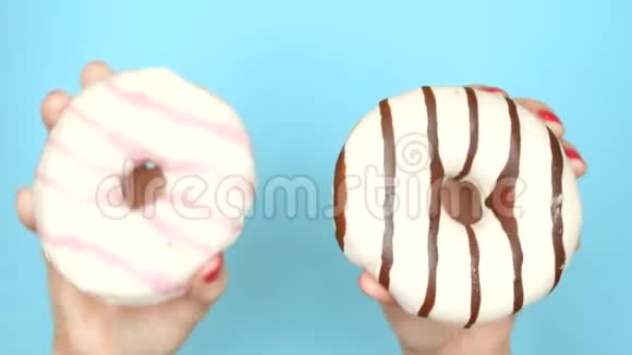 巧克力甜甜圈和草莓甜甜圈的概念选择有红色指甲油的女性手拿着粉红色和棕色甜甜圈视频的预览图
