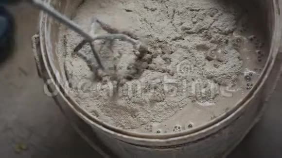 电动搅拌机将水泥混合在施工现场的桶中视频的预览图