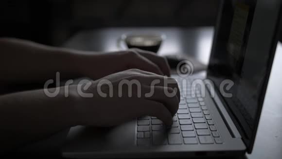 晚上一个男人坐在一张桌子旁喝咖啡吃饼干用笔记本电脑工作视频的预览图