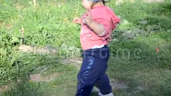 微笑可爱好玩的小女孩站在绿草上女孩蹒跚学步在湖边散步学会走路阳光明媚视频的预览图