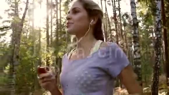 迷人的年轻女子在森林里奔跑以保持健康视频的预览图