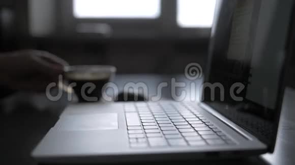 男人晚上工作手提电脑和一杯热咖啡蒸发在靠窗的桌子上喝咖啡玩得开心视频的预览图