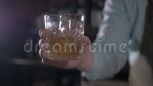 手拿着一杯威士忌在酒吧的岩石上男人在酒吧里摇酒视频的预览图