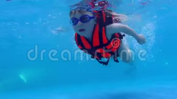 幼儿在水下游泳慢动作穿救生衣的儿童在水下游泳视频的预览图