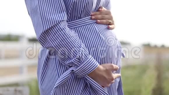近距离观看大自然中怀孕的腹部女人抱着花束抚摸她的腹部视频的预览图
