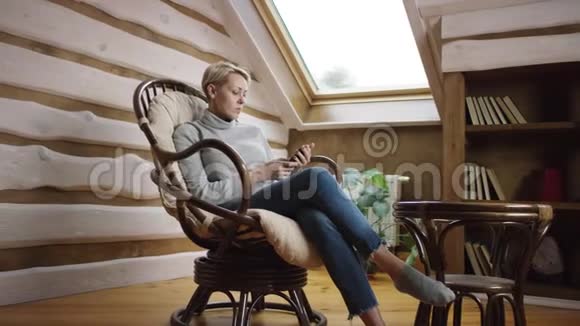 坐在椅子上的女人在智能手机上发短信视频的预览图