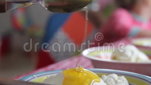 瓶装奶酪酸奶油和蜂蜜在盘子里孩子们要吃白奶酪和彩色盘子里的酸奶油科特视频的预览图