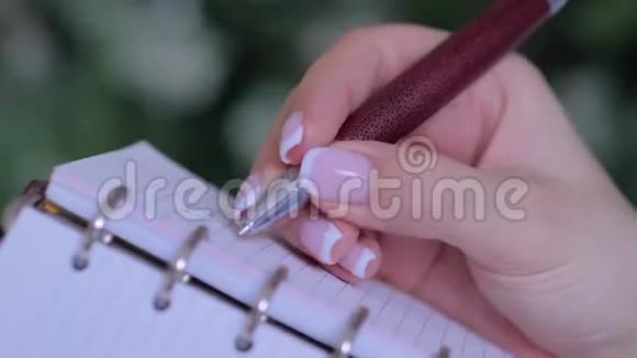 女人手拿笔写字在老式笔记本电脑组织者做清单视频的预览图