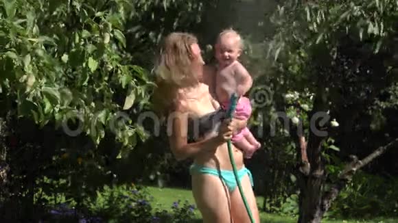 漂亮的妈妈穿着内衣小女儿在花园里的水里提神4K视频的预览图