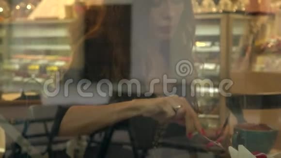 漂亮的黑发女孩在糕点店吃蛋糕从窗外看4K视频视频的预览图