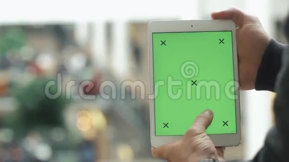 男人手里拿着绿色的屏幕展示着白色的平板电脑视频的预览图