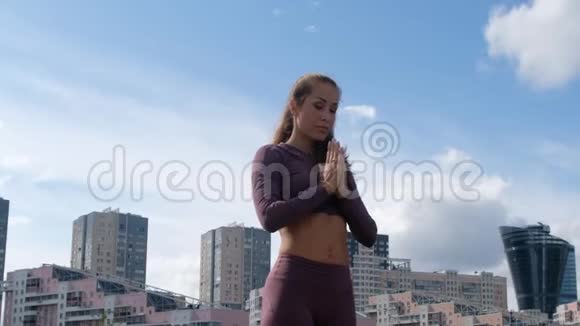 年轻女子做瑜伽运动与城市背景呼吸放松和自由的概念视频的预览图