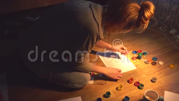 年轻女孩艺术家在木地板上用水彩颜料创作插图视频的预览图