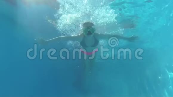 游泳池水下戴面具的快乐女孩看镜头泡泡阳光视频的预览图