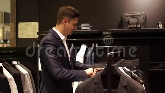 男人从店里的生衣中挑选商务夹克视频的预览图