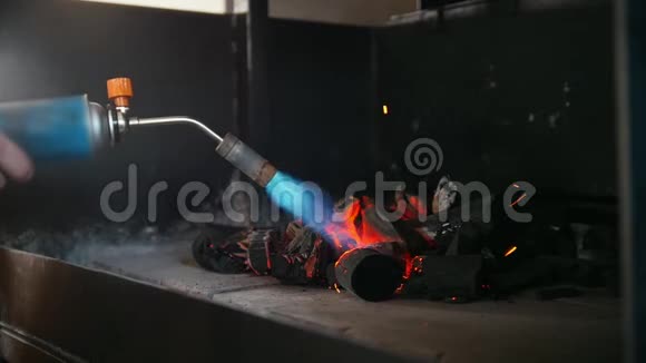 在烧烤炉里用煤气燃烧器点燃木炭视频的预览图
