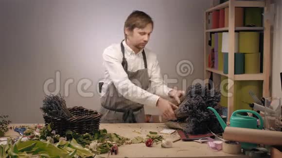 年轻的男花匠花店里拿着一壶熏衣草视频的预览图